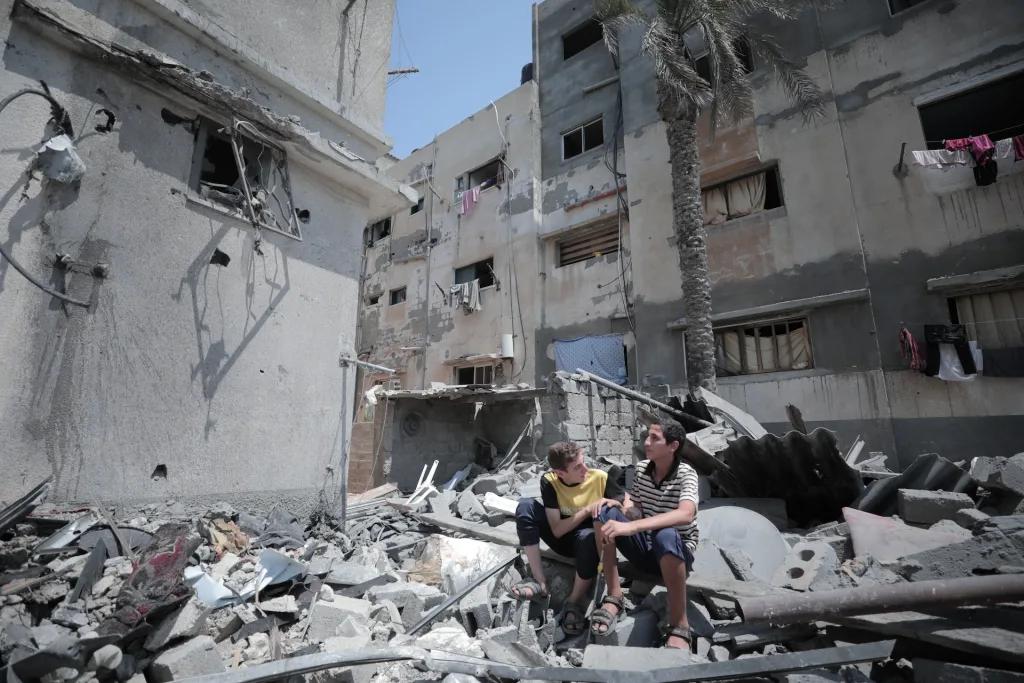 Kaksi palestiinalaista poikaa istuu Israelin tuhoamien palestiinalaisten kotien raunioiden päällä keskellä päivää.